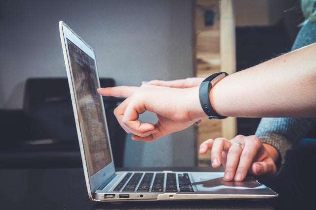 hands pointing to a laptop screen